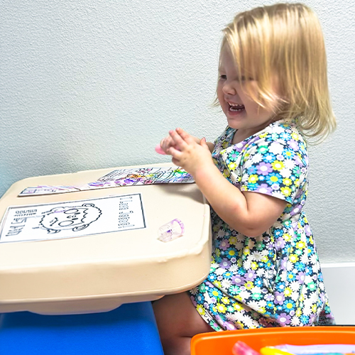 A young girl laughing while coloring during a Sunday morning kids ministry program at Centerpoint Church in Rogers, AR